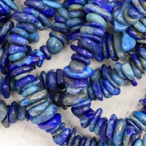 May include: A strand of blue and white lapis lazuli gemstone beads. The beads are irregular in shape and have a natural, rough texture.