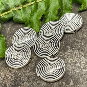 May include: Six silver metal round beads with a spiral design. The beads have a hole in the center for stringing.