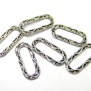 May include: Six silver oval-shaped metal rings with a decorative, ornate design. The rings are all the same size and have a smooth, polished finish.