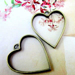 May include: Two antique gold-toned metal heart-shaped frames. The frames are empty and ready to be filled with photos, pressed flowers, or other small treasures.