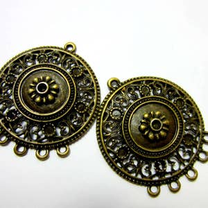 Peut inclure: Deux pendentifs en filigrane de couleur bronze antique. Chaque pendentif pr&eacute;sente un motif floral central entour&eacute; de motifs ajour&eacute;s complexes. Les pendentifs ont des boucles pour suspendre et de petites boucles pour attacher des &eacute;l&eacute;ments suppl&eacute;mentaires.