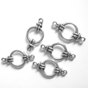 May include: Five silver-toned metal clasps with a decorative knot design. Each clasp has a circular ring and two loops for attaching to jewelry or other crafts.