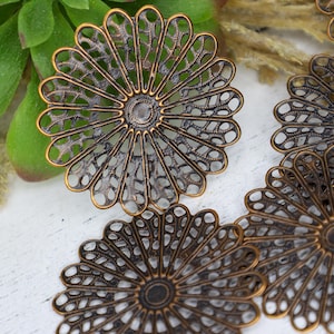 May include: Four antique gold metal filigree flower shapes with a detailed design. The flower shapes are round and have a center circle.