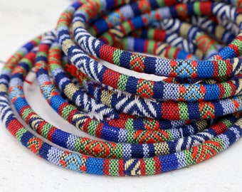 May include: A close-up of a bundle of colorful, patterned fabric cord. The cord is woven with blue, red, green, and white stripes.