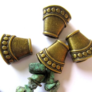 Puede incluir: Cuatro tapones de extremo de metal de color dorado antiguo con un borde de cuentas decorativas. Los tapones de extremo tienen forma de cono y tienen una parte superior redondeada.