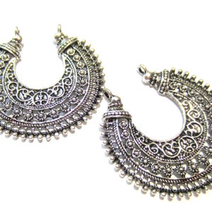 May include: Two silver filigree crescent moon shaped metal charms with a decorative design.