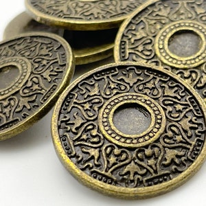 May include: A set of six antique gold-toned metal decorative coins with intricate floral designs. Each coin has a raised center circle with a smooth surface.