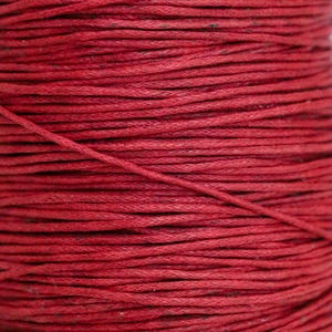 Könnte beinhalten: Nahaufnahme einer Spule mit rotem gewachstem Baumwollgarn. Das Garn ist fest gewickelt und hat eine glatte, polierte Oberfläche.