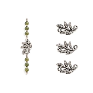 May include: A vertical strand of six small, round, olive-green beads interspersed with silver-toned metal spacers and a central silver-toned leaf-shaped connector, alongside three individual silver-toned metal leaf-shaped connectors.