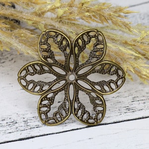 May include: A bronze-colored metal flower charm with a delicate, intricate design. The charm has a circular hole in the center, suggesting it can be used for jewelry making or crafting.