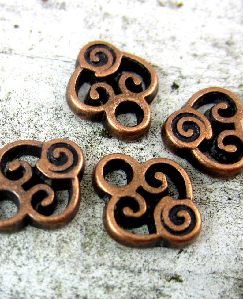 Puede incluir: Cuatro abalorios de metal de color cobre con un dise&ntilde;o de nudo celta en espiral. Cada abalorio tiene un di&aacute;metro de aproximadamente 2,5 cm.