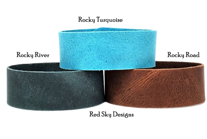 K&ouml;nnte beinhalten: Drei Lederarmb&auml;nder in verschiedenen Farben: T&uuml;rkis, Dunkelblau und Braun. Die Armb&auml;nder sind &uuml;bereinander gestapelt. Der Text "Rocky Turquoise", "Rocky River" und "Rocky Road" steht &uuml;ber jedem Armband. Der Text "Red Sky Designs" steht unter den Armb&auml;ndern.