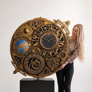 Puede incluir: Un gran reloj circular dorado de estilo antiguo con una esfera central de números romanos, rodeada de símbolos del zodiaco. Incluye un globo terráqueo azul, un indicador de fase lunar con la etiqueta 'over the moon' y engranajes mecánicos.