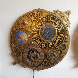 May include: A large, ornate brass-colored wall clock with multiple dials and gears. The clock features a central clock face with Roman numerals, zodiac symbols, and a celestial map. Additional dials display a globe and other astronomical elements.