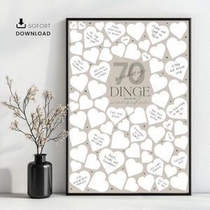 May include: A framed print with a beige background and numerous white heart shapes. The print features the number "70" and German text, with the word "SOFORT DOWNLOAD" in the upper left corner. A black vase with a plant is in the foreground.