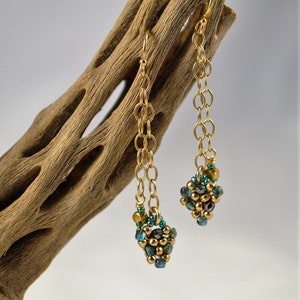 May include: Gold chain earrings with a cluster of teal and gold beads at the bottom.