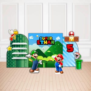 Może przedstawiać: Dekoracja imprezowa z motywem Super Mario, zawierająca centralne tło z napisem Super Ethan, zielonymi wzg&oacute;rzami i niebieskim niebem. Zestaw zawiera wycięte postacie Mario, Luigiego, skrzydlatego Koopa Troopa, roślinę Piranha oraz dużą czerwoną cyfrę 5.