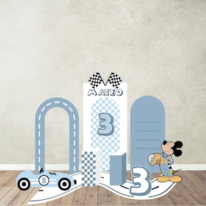 May include: A light blue race car and road design with the number 3, checkered flags, and the name "Mateo". A cartoon mouse in a racing outfit is also present. The design is on a wooden surface.