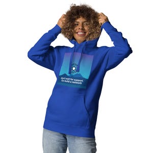 Puede incluir: Una sudadera con capucha azul real con un diseño gráfico que presenta una forma geométrica azul y blanca sobre una cordillera con un fondo degradado de azul, morado y rosa. El texto "don't wait for support. Go build a network" está impreso debajo del gráfico.