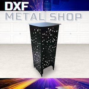 Peut inclure: Un présentoir décoratif en métal noir avec un dessus carré et un corps rectangulaire. Le corps présente un motif découpé de différentes formes. Le texte "DXF METAL SHOP" est affiché en haut de l'image.