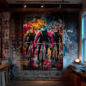 May include: A large painting shows three cyclists racing. They wear helmets and cycling gear in red, yellow, and black. The background is a vibrant mix of graffiti art with splashes of colour.