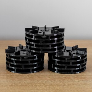 May include: Three black plastic filter cartridges stacked on top of each other. Each cartridge has a series of circular ridges.