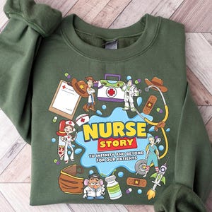 Pu&ograve; includere: Felpa verde con una grafica colorata che recita "Nurse Story" con personaggi dei cartoni animati e forniture mediche. Il testo "To infinity and beyond for our patients" &egrave; incluso.