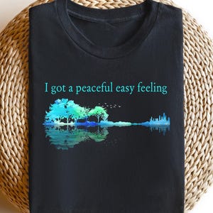 May include: Black t-shirt with a blue and green watercolor guitar design and the text "I got a peaceful easy feeling".