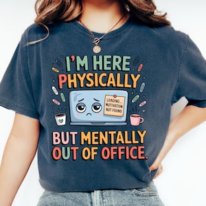 Puede incluir: Camiseta azul oscuro con el texto "I'M HERE PHYSICALLY BUT MENTALLY OUT OF OFFICE." El gráfico incluye un portátil triste, tazas de café y clips. La camiseta se usa con vaqueros azules y zapatos blancos.