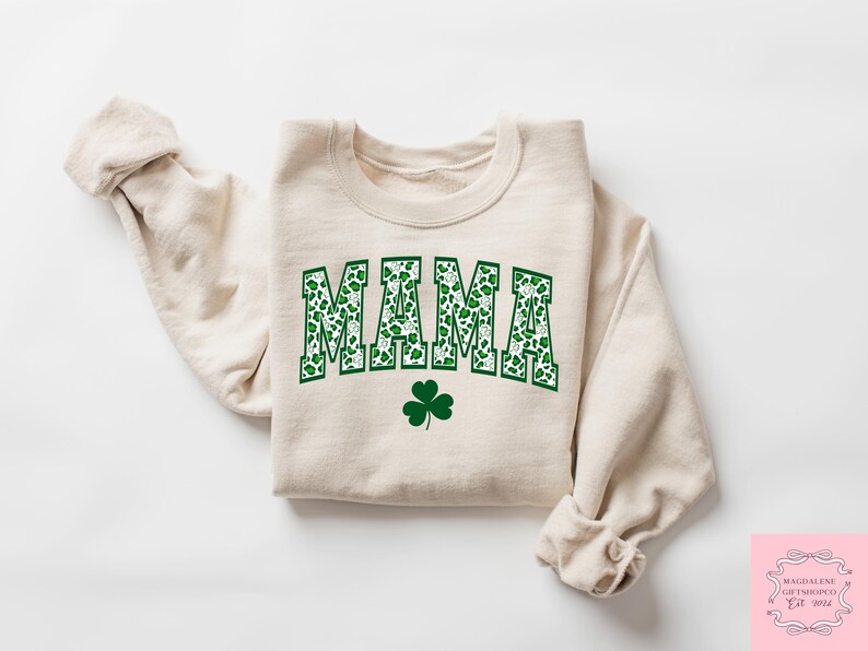 May include: A beige sweatshirt with a green shamrock design and the word "MAMA" in green and white shamrock print.