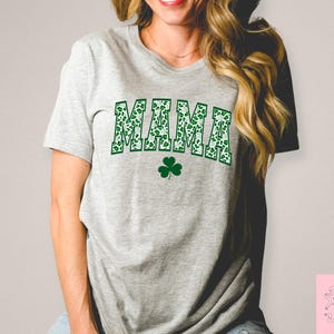 May include: A gray t-shirt with a green shamrock print that says "MAMA" in green shamrock letters.