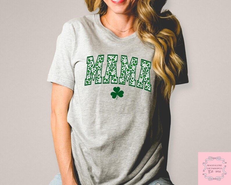 May include: A gray t-shirt with a green shamrock print that says "MAMA" in green shamrock letters.