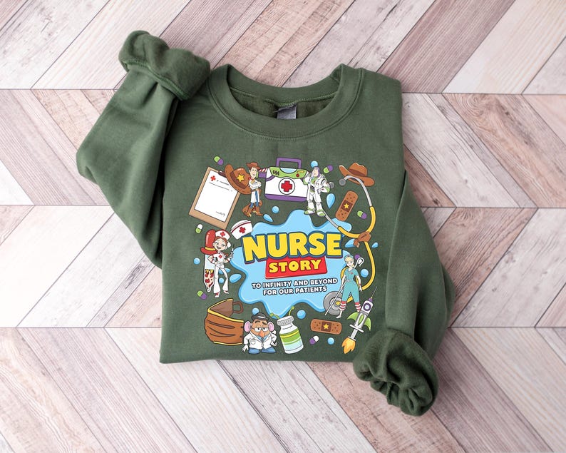Pu&ograve; includere: Felpa verde con una grafica colorata che recita "Nurse Story" con personaggi dei cartoni animati e forniture mediche. Il testo "To infinity and beyond for our patients" &egrave; incluso.