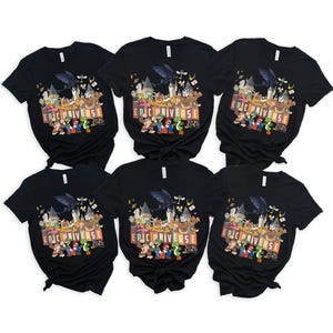 May include: Six black t-shirts with a colorful graphic featuring various cartoon characters and the text "EPIC UNIVERSE 2026". The design includes a dragon, castle, and several video game characters.