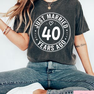 May include: A gray t-shirt with a white circle graphic that says "Just Married 40 Years Ago" with a heart symbol.