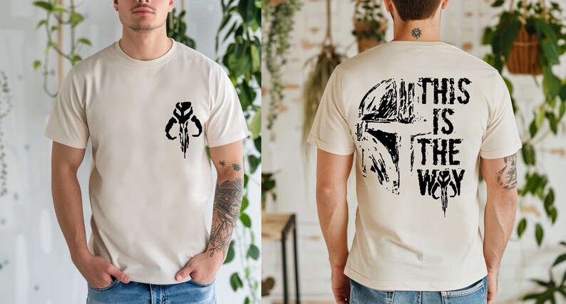 May include: Beige t-shirt with a black graphic on the front and back. The front features a stylized skull design. The back displays a helmet graphic and the text "THIS IS THE WAY".