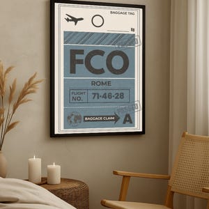 Peut inclure: Impression encadrée d'une étiquette de bagage vintage pour l'aéroport FCO de Rome. Le design présente un code couleur bleu et blanc avec le numéro de vol 71-46-28. L'impression est dans un cadre noir, dans une pièce avec des bougies et une chaise.