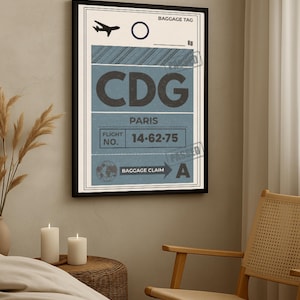 Peut inclure: Une affiche encadrée d'une étiquette de bagage vintage pour Paris, France. L'étiquette affiche le code aéroportuaire "CDG" en grandes lettres, ainsi que le numéro de vol "14-62-75" et un indicateur de réclamation de bagages.