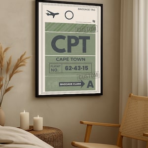 Puede incluir: Una impresión enmarcada de una etiqueta de equipaje vintage para Ciudad del Cabo (CPT). El diseño presenta una combinación de colores verde y crema con el texto "CPT", "Cape Town" e información de vuelo. La impresión está en un marco negro.
