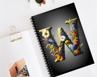 Pode incluir: Um caderno espiral preto com um design de letra W floral. A letra é feita de folhas verdes e flores coloridas. O fundo é um degradê de cinza escuro.