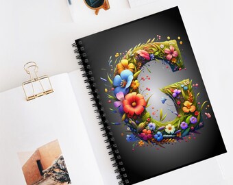 May include: A black spiral notebook with a colorful floral design forming the letter "G" on the cover. The flowers are in shades of pink, red, yellow, blue, and purple.