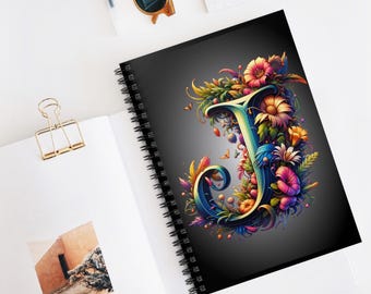 May include: A black spiral notebook with a colorful floral design featuring the letter "J" in the center. The design is vibrant and intricate, with a variety of flowers, leaves, and butterflies.