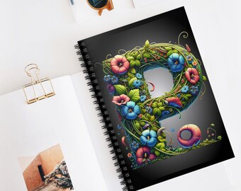 May include: A black spiral notebook with a colorful floral design forming the letter "P". The flowers are pink, blue, and green.