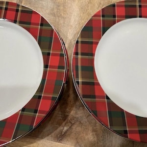 May include: A set of white ceramic plates with a red, green, and brown plaid border. The plates are arranged on a wooden surface, showcasing a festive, holiday-themed design. The plaid pattern adds a classic touch.