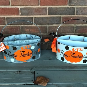 Puede incluir: Dos porta cubiertos de metal con temática de Acción de Gracias con lunares naranja, negro y blanco. Los porta cubiertos tienen un diseño de calabaza y el texto "Happy Thanksgiving".