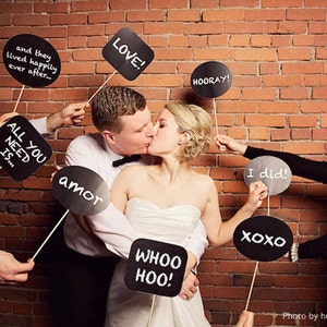 May include: A group of people holding up black chalkboard signs with various phrases written in white chalk, including "LOVE!" "HOORAY!" "I did!" "ALL YOU NEED IS..." "amor" "WHOO HOO!" and "XOXO".