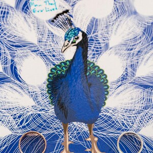 close up of a peacock with wedding rings either side and guests messages inside the peacock feathers