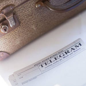 vintage style telegram wedding guest book cards stacked besides a vintage suitcase