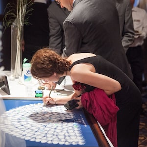 wedding guest signing a peacock guest book poster