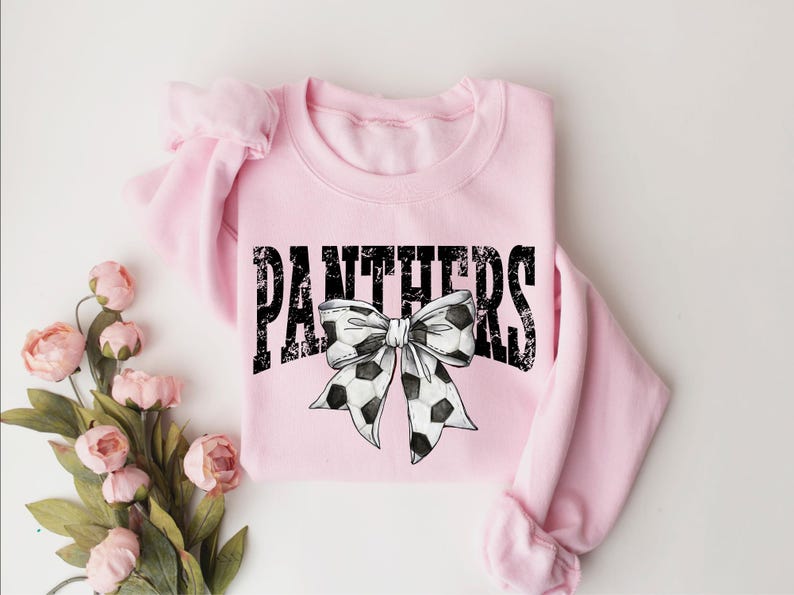 A pink sweatshirt with the word "PANTHERS" and a soccer ball bow printed on it, along with some pink flowers.